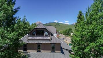 A lodge named Elk Mountain Lodge with a prominent sign, surrounded by lush greenery and a mountainous backdrop.