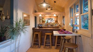 En hyggelig bar med træbænke, bardisk og hængende lamper.
