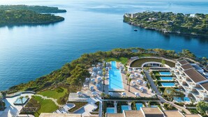 Un complexe hôtelier doté de plusieurs piscines, dont une grande piscine centrale, et offrant une vue sur la mer.