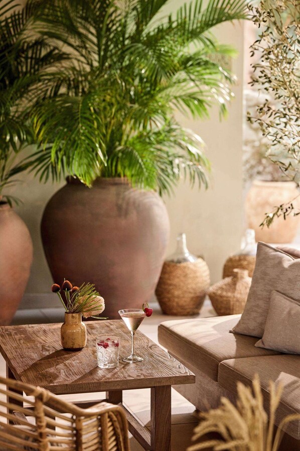 Ein gemütliches Interieur mit einem Holztisch, einer Couch und großen Topfpflanzen.