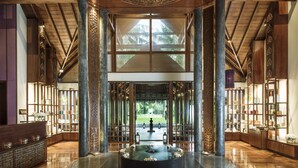 A spacious lobby with a central water feature, high ceilings with intricate woodwork, and a view of a tropical garden.