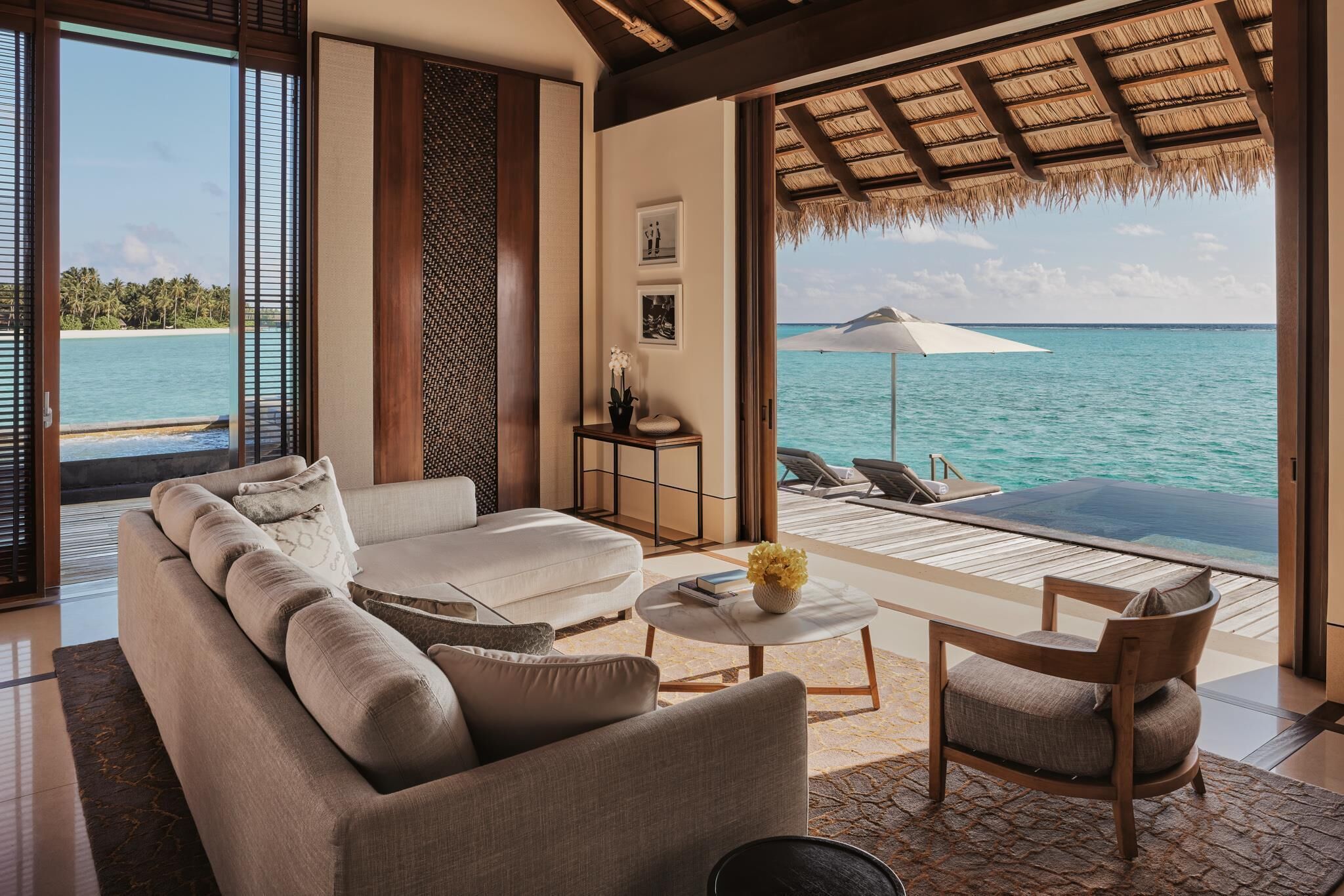 Un salón moderno con un sofá, una mesa de centro y una silla, con vistas a una piscina privada y al océano.
