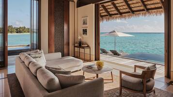 Un salón moderno con un sofá, una mesa de centro y una silla, con vistas a una piscina privada y al océano.