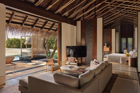 A modern living room with a large sofa, a flat-screen TV, and a seating area with chairs.