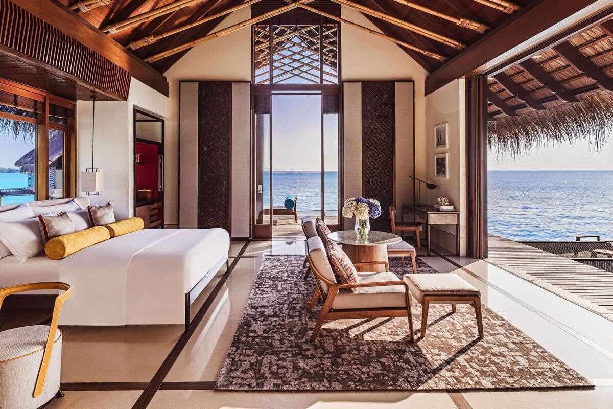 Une chambre à coucher luxueuse dotée d’un grand lit, d’un coin salon et offrant une vue sur l’océan.