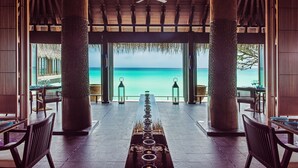A covered outdoor seating area with a view of the ocean. - One&Only Reethi Rah (Reethi Rah)