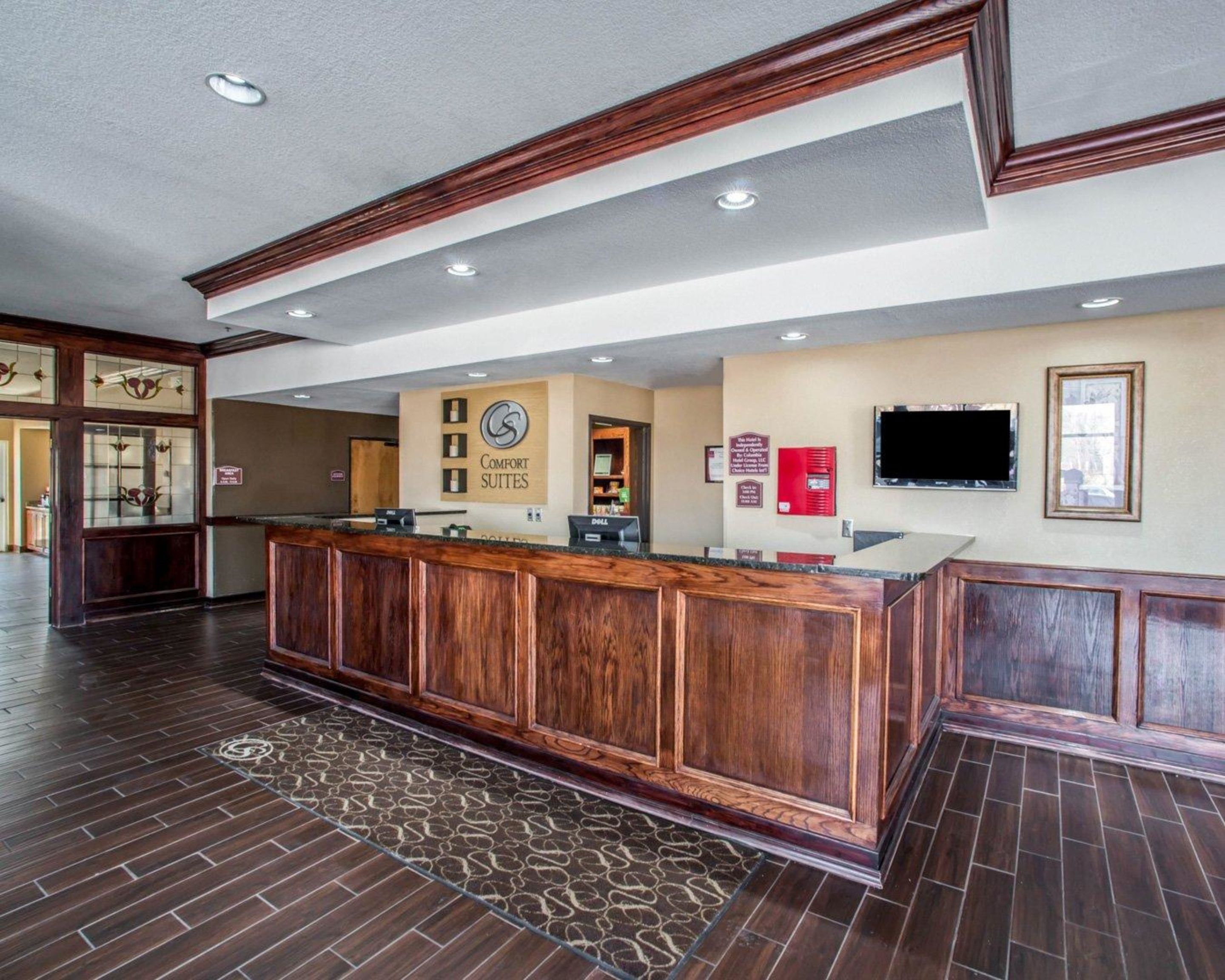 A reception area with a wooden reception desk, a clock, and a television mounted on the wall.