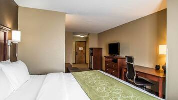 A hotel room with a bed, a desk, a chair, a television, and a door leading to another room.