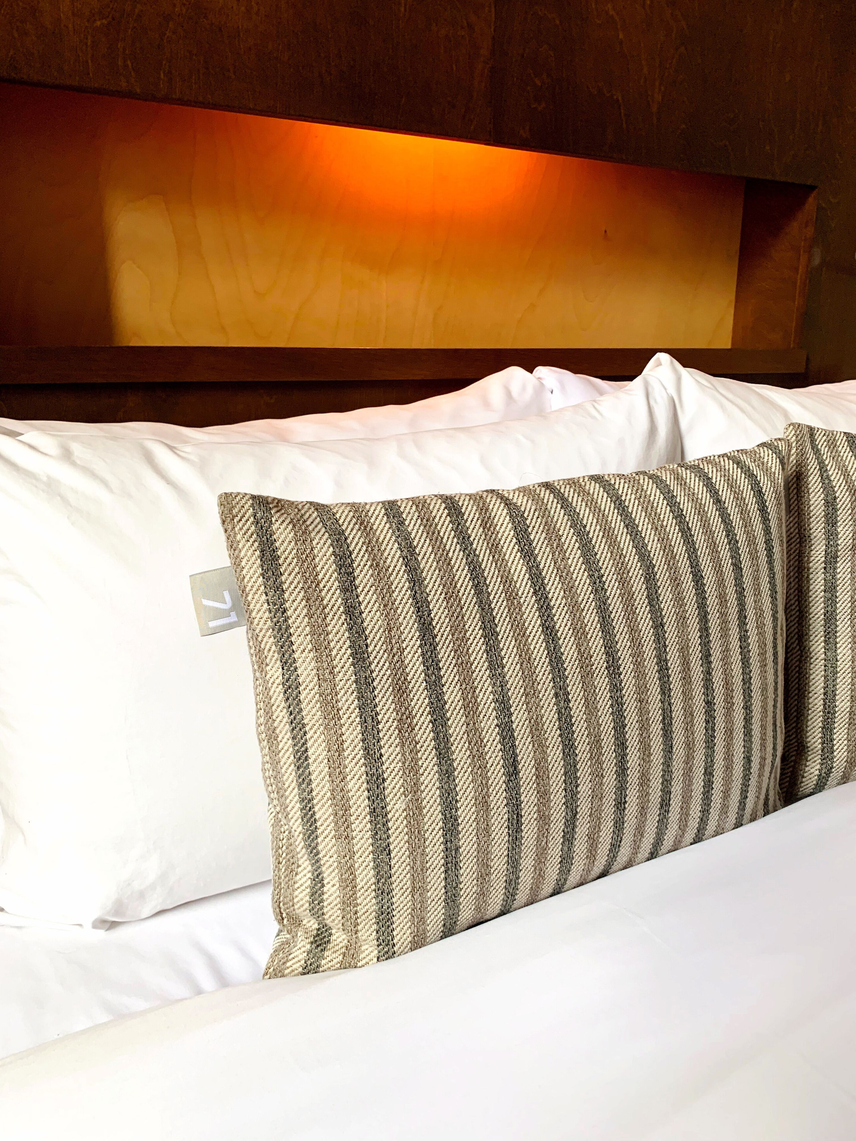 Una cama con almohadas blancas y una de rayas.