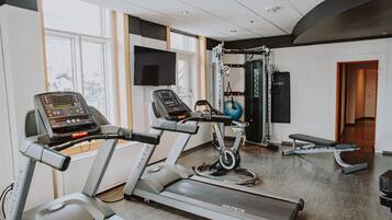 Ein Fitnessraum mit Laufbändern, einem Ergometer und einer Hantelbank.