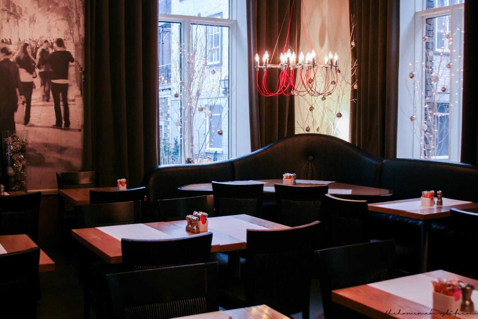 Un restaurant acollidor amb interior modern, que destaca una fusteria tapissada de color negre, diverses taules i una làmpada penjant.