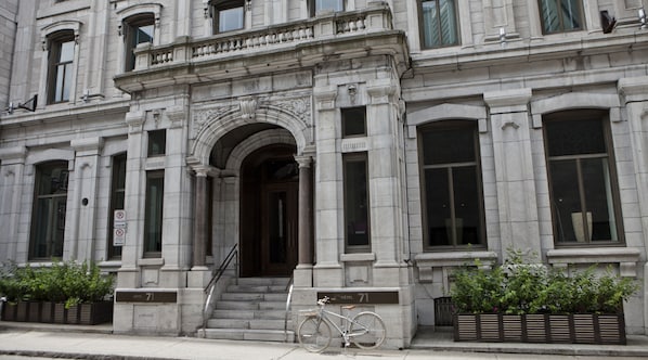 Un bâtiment historique doté d’une entrée imposante, avec un vélo garé devant et une enseigne indiquant qu’il s’agit d’un hôtel.