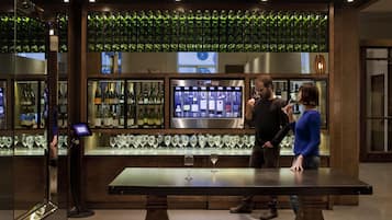 Un espace bar doté d’un kiosque numérique présentant une sélection de vins, d’un présentoir réfrigéré pour les bouteilles et d’un comptoir en bois.