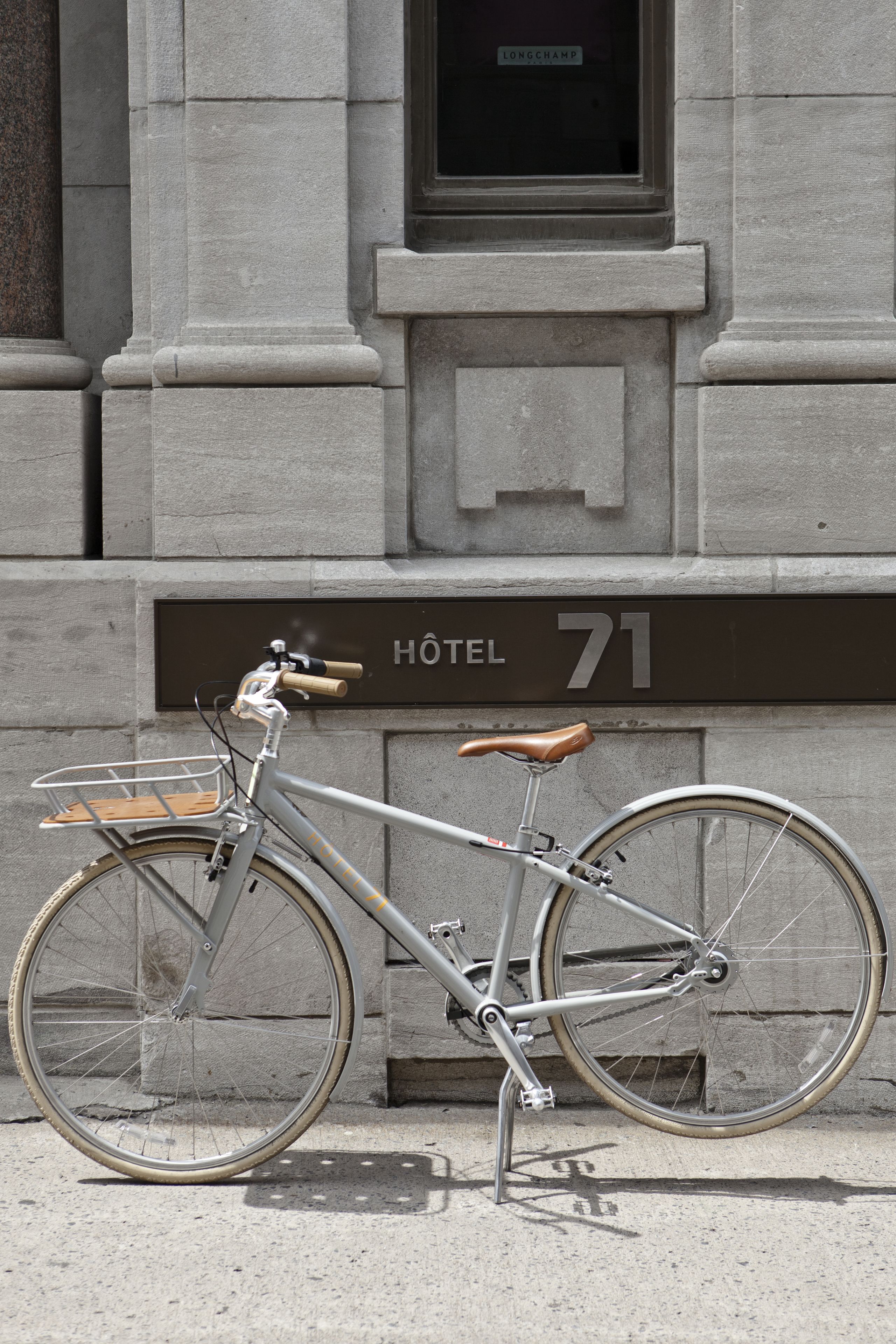 Un vélo est garé devant un immeuble sur lequel on peut lire l’inscription « HÔTEL 71 ».