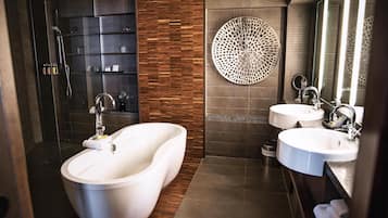 Ein modernes Badezimmer mit einer freistehenden Badewanne, zwei Waschbecken, einer Dusche und dekorativen Wandverkleidungen.