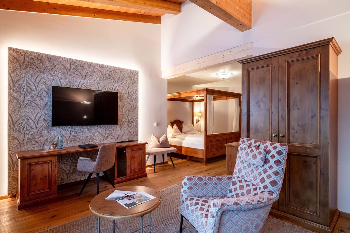 Una habitación con escritorio de madera, televisión, pared con diseño, cama y armario.