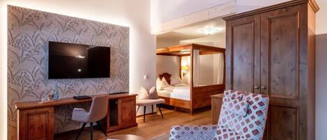 A room with a wooden desk, a television, a patterned wall, a bed, and a wardrobe.