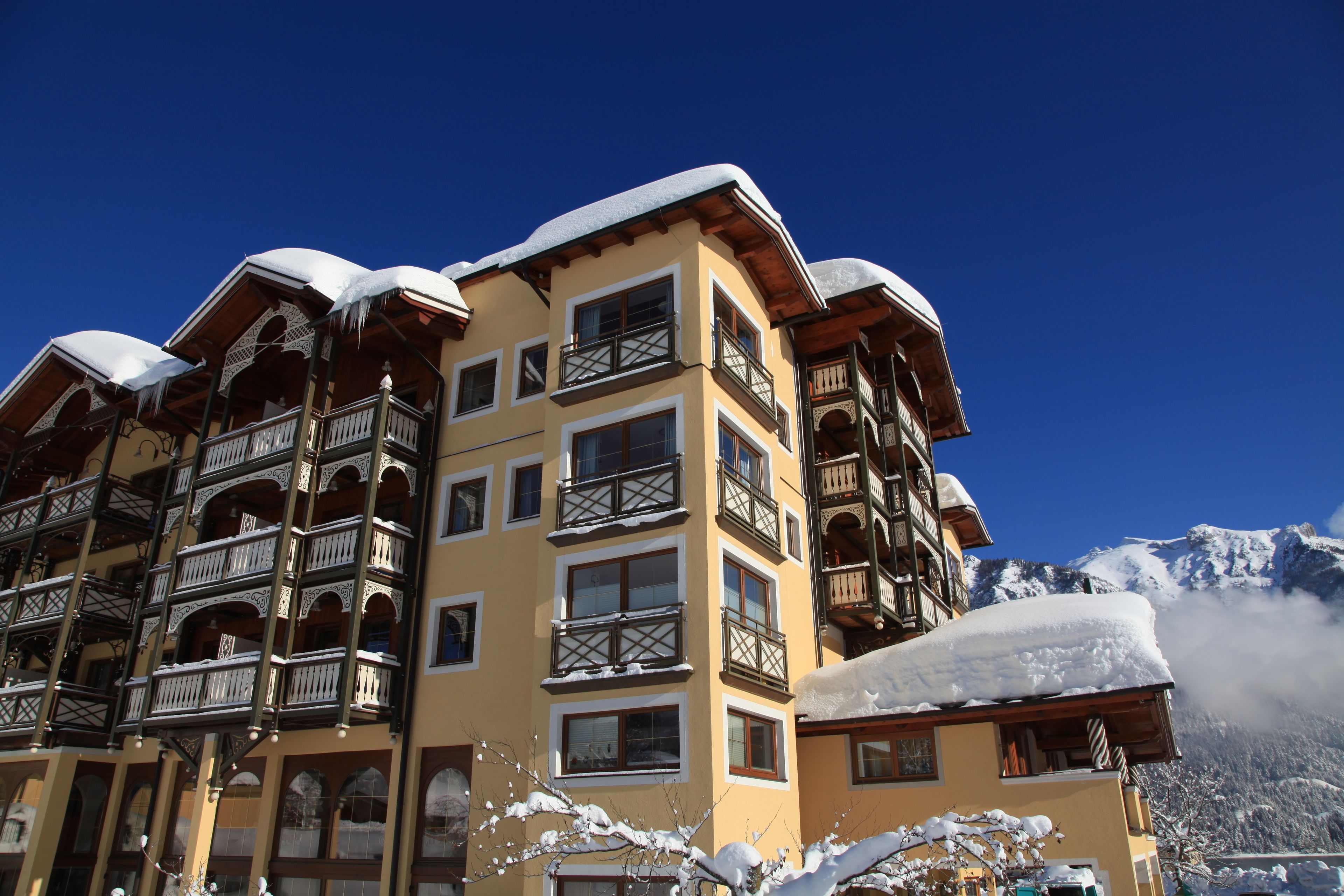 Een hotel met meerdere verdiepingen, balkons en een berg op de achtergrond.