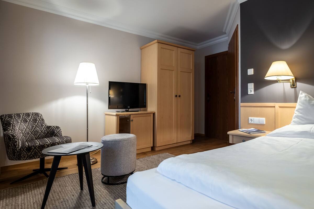 Una habitación de hotel con cama, televisión, escritorio, silla y armario.