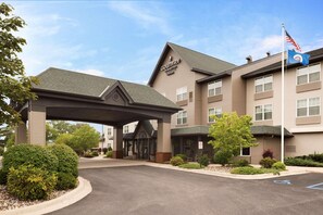 A Country Inn & Suites hotel with a covered entrance, a flag, and a parking lot.