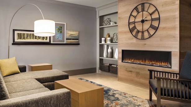 Una sala de estar moderna con chimenea, un reloj de pared grande y un sofá.