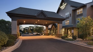 Entrada de un hotel con un corredor cubierto, un letrero que indica 'Country Inn & Suites' y un letrero de 'No Estacionar'.