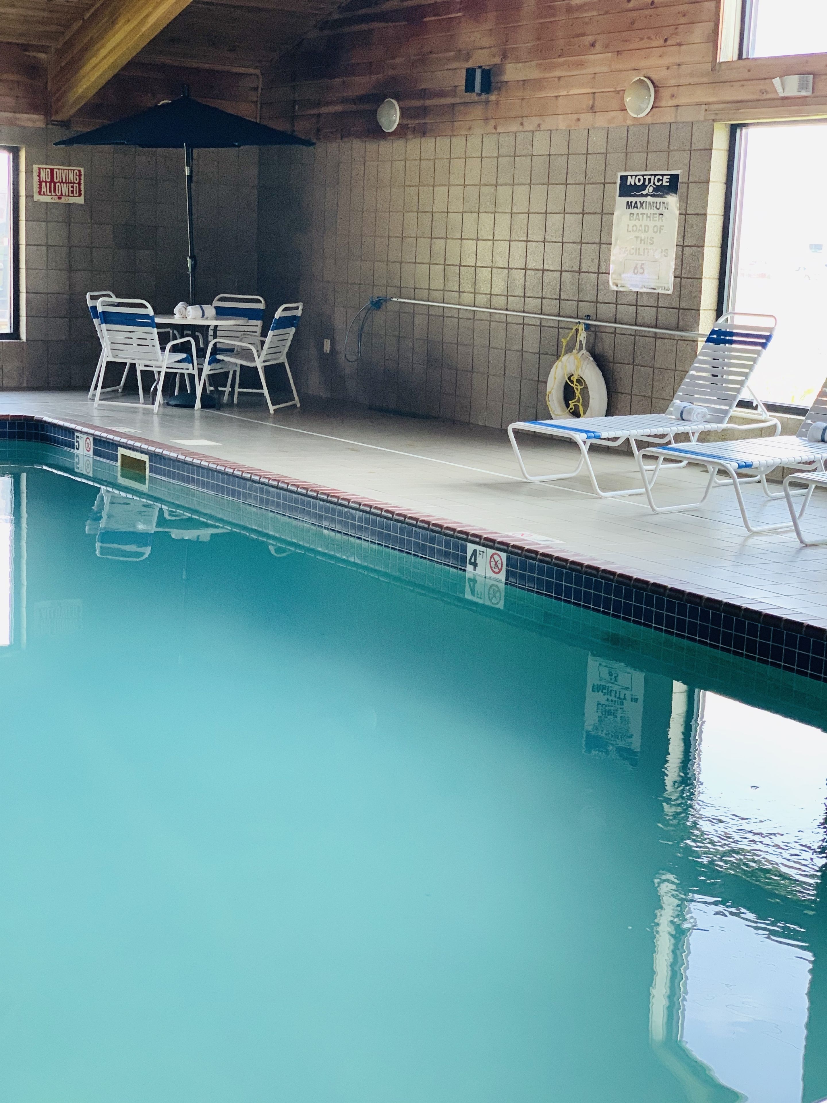 An indoor swimming pool with lounge chairs and a table.