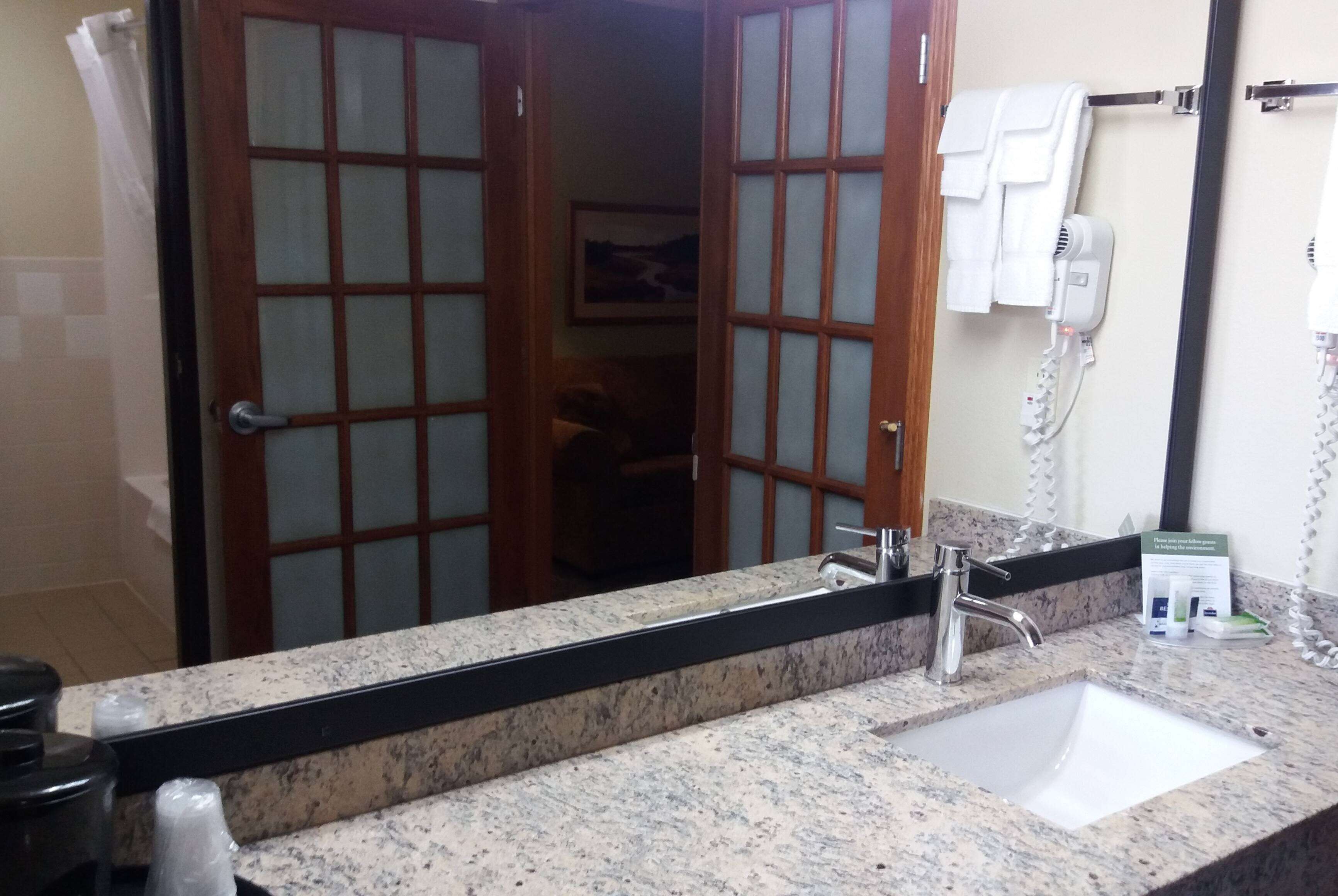 Une salle de bain avec un comptoir en granit, un lavabo, un miroir et un porte-serviettes.