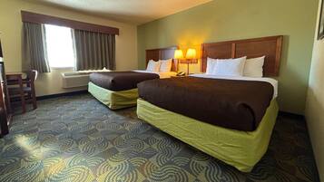 A hotel room with two beds, a desk, and a chair.