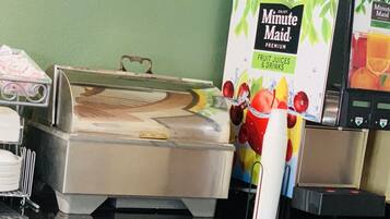 Disposição de buffet com uma lixeira identificada com a etiqueta 'TRASH' e um refrigerador de suco Minute Maid.