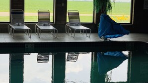 A pool area with four lounge chairs and a potted plant. - AmericInn by Wyndham Kewanee (Kewanee)
