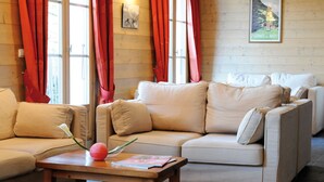 Un salon chaleureux avec un canapé beige, une table basse en bois et des rideaux rouges.