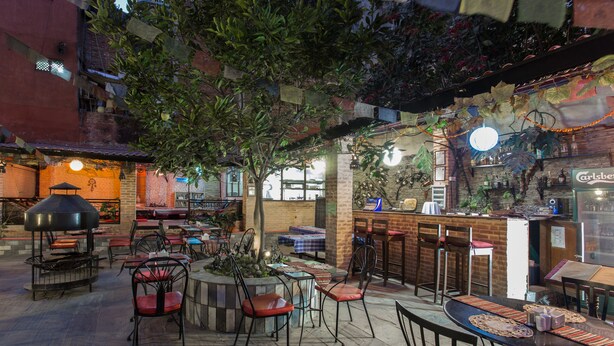 An outdoor dining area with tables and chairs, a bar, and a tree. - Hotel Encounter Nepal (Kathmandu)