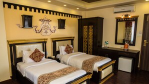A hotel room with two beds, a small desk, a mirror, and an air conditioning unit. - Hotel Encounter Nepal (Kathmandu)