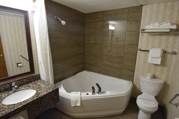A bathroom with a freestanding bathtub, a sink, a toilet, and a towel rack. - Tropical Inn (North Battleford)