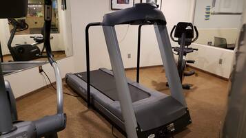 Un gimnasio en casa con una cinta de correr, una bicicleta estática y equipo de ejercicio.