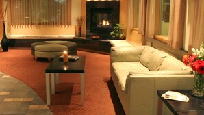 A living room with a sofa, ottoman, coffee table, and a fireplace.