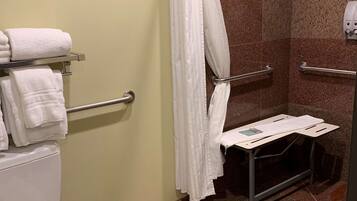 A bathroom with a toilet, a shower with a glass door, and a towel rack with folded towels.