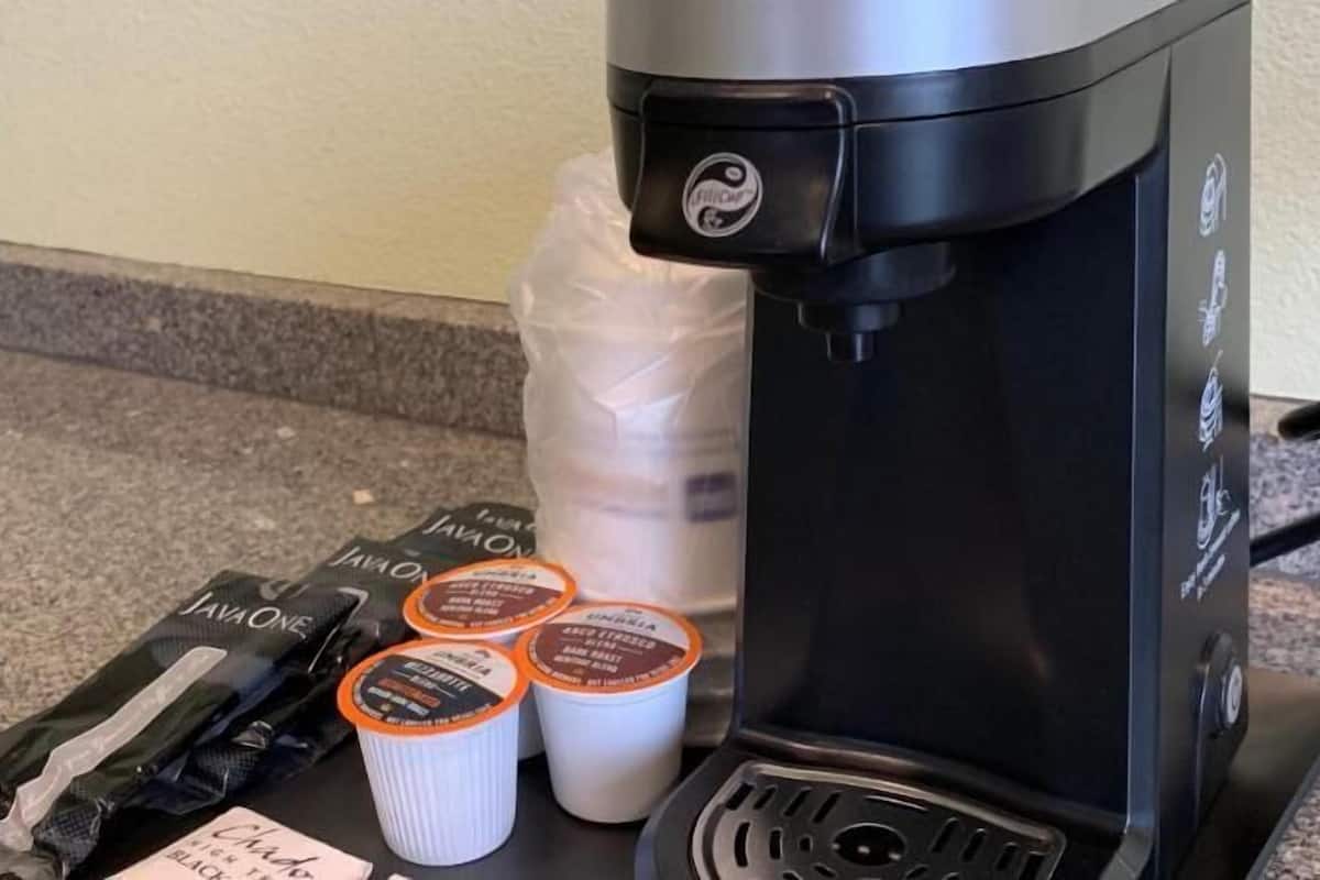 A coffee maker, a milk jug, and coffee pods on a countertop.