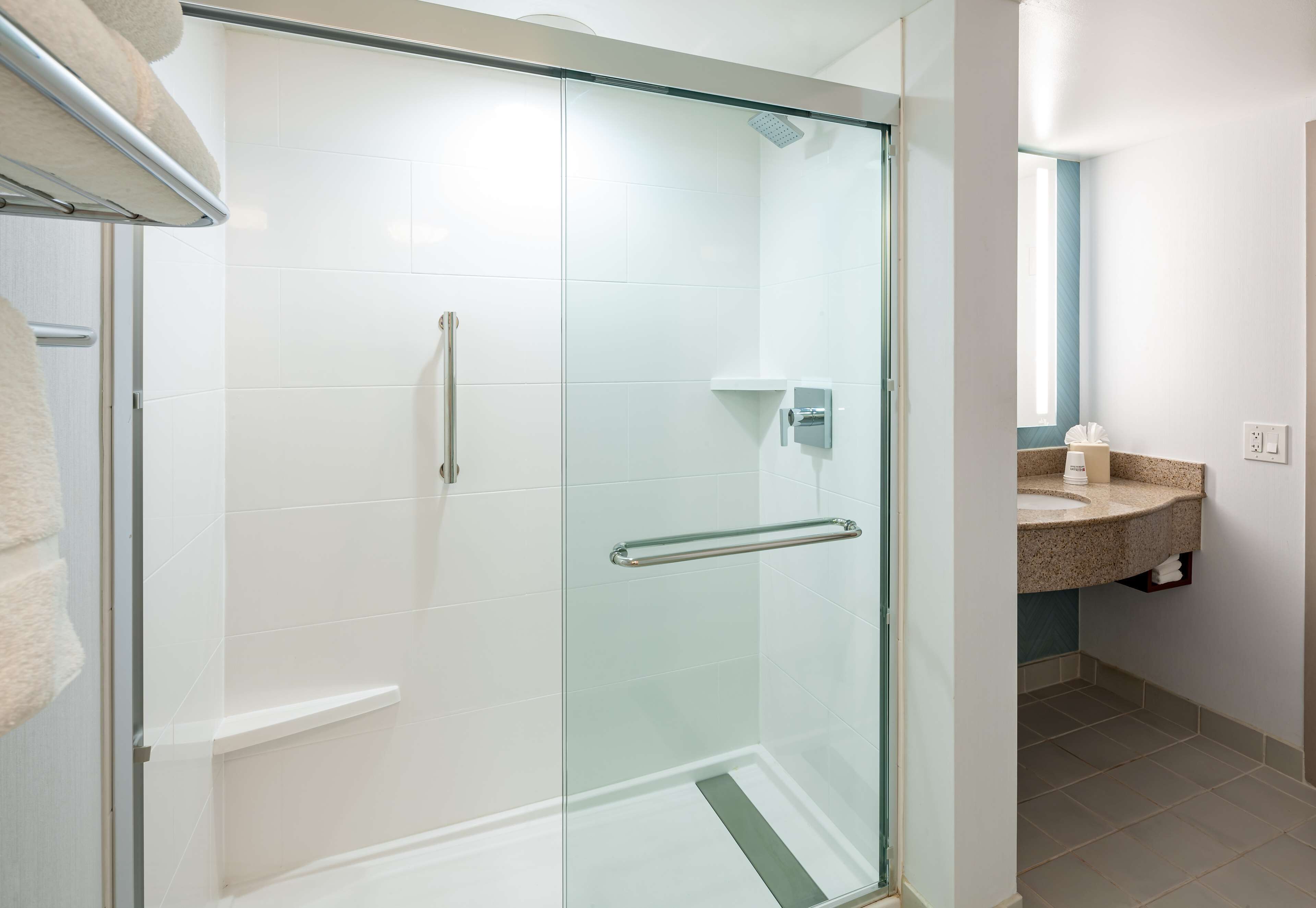 A modern bathroom with a glass-enclosed shower, a vanity with a granite countertop, and a towel rack.