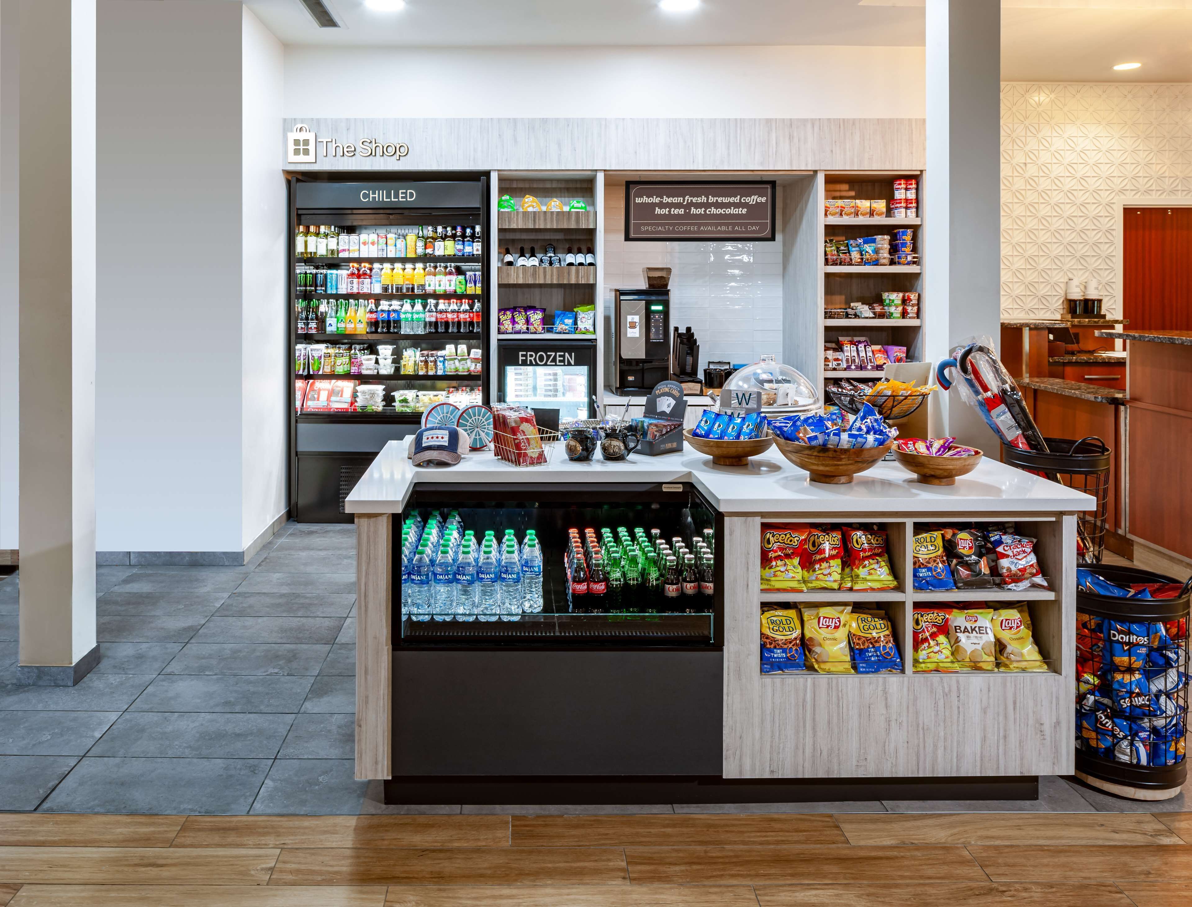 A snack bar with chilled and frozen beverages, a coffee station, and a variety of snacks including chips and bottled water.