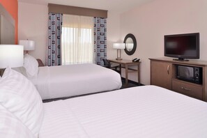 A hotel room with two beds, a desk with a chair, a television, a telephone, and a microwave.