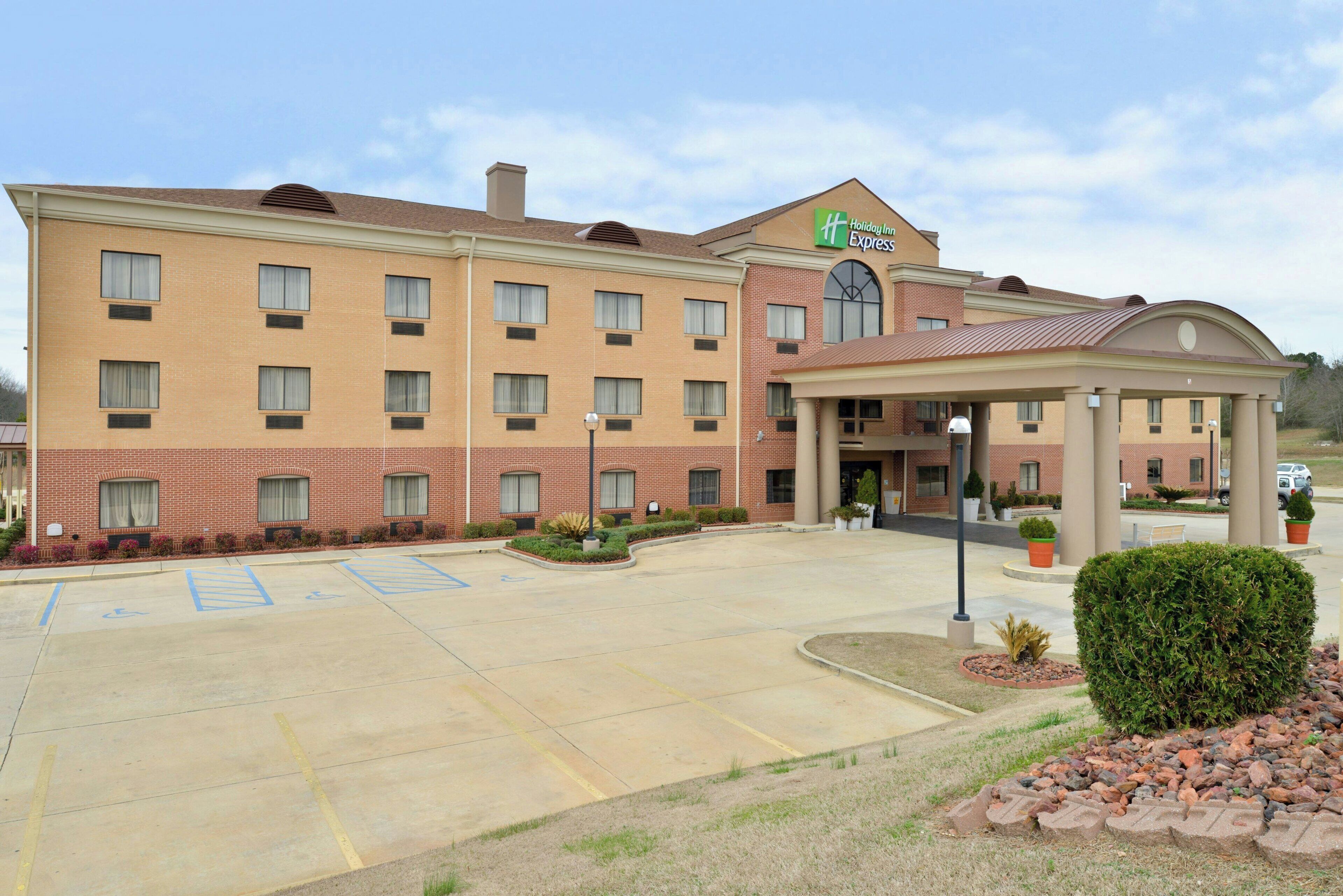 Un hotel Holiday Inn Express con estacionamiento, espacios accesibles para sillas de ruedas y una entrada cubierta.