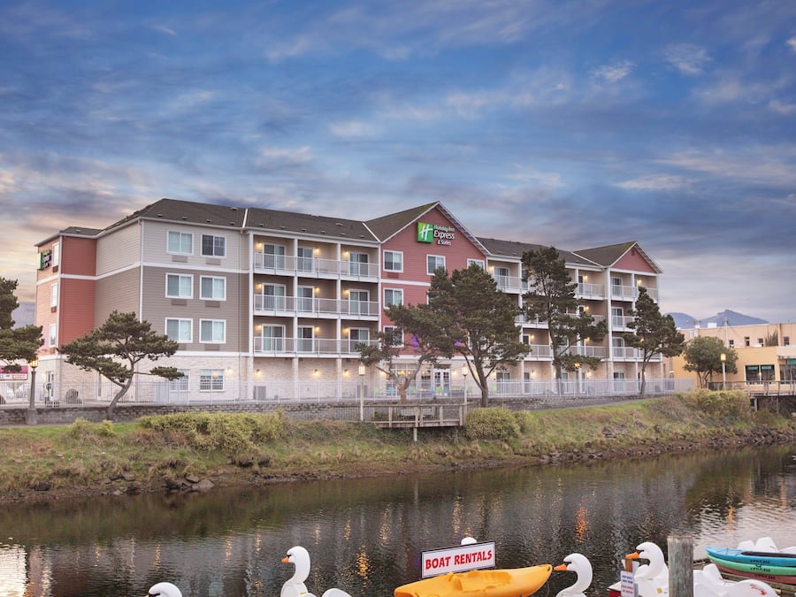 A multi-story hotel with balconies, a sign for boat rentals, and a body of water in the foreground.
