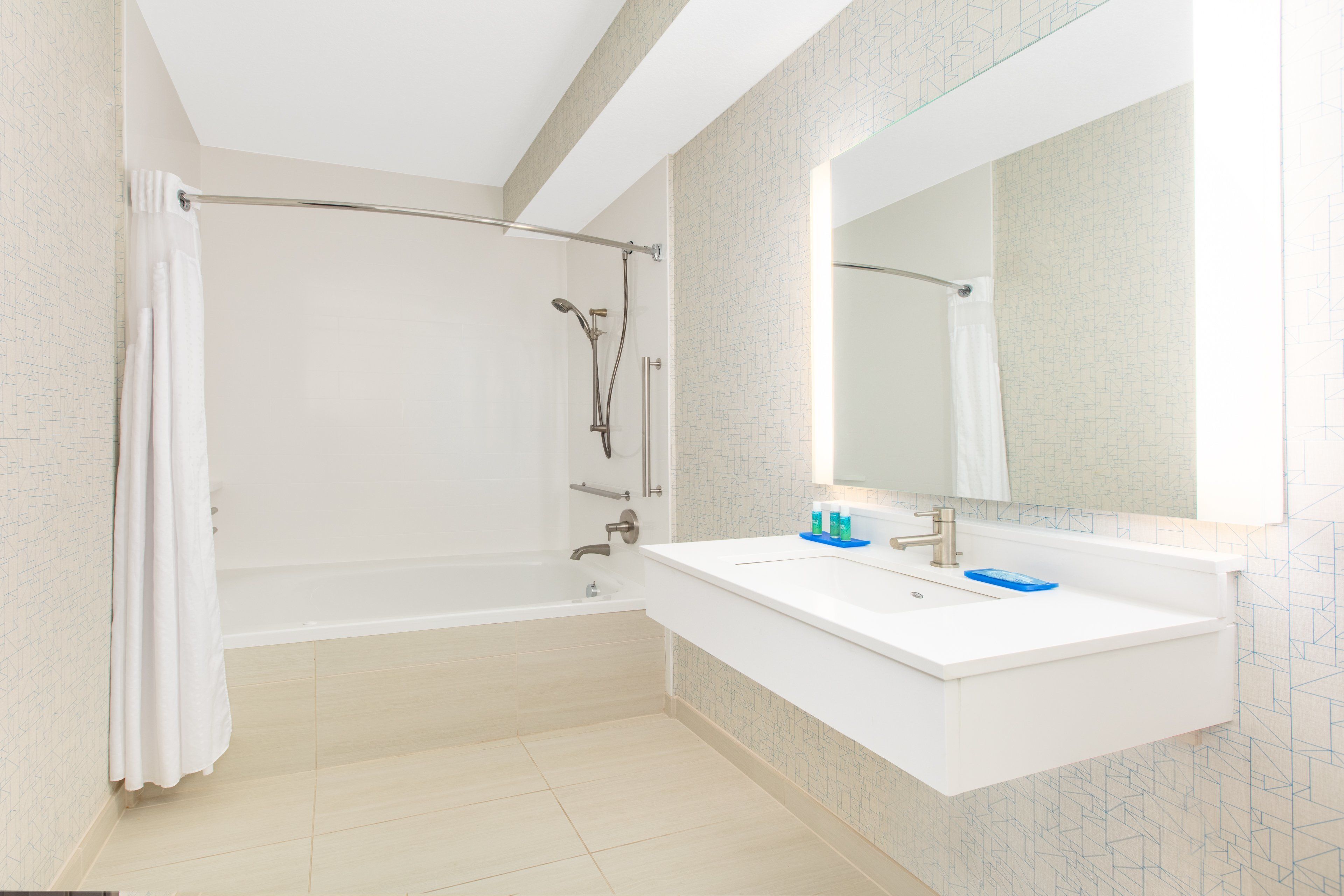 A modern bathroom with a walk-in shower, a white sink, and a large mirror.