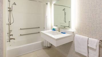 A modern bathroom with a bathtub, a shower, a sink with a mirror, and a towel rack.