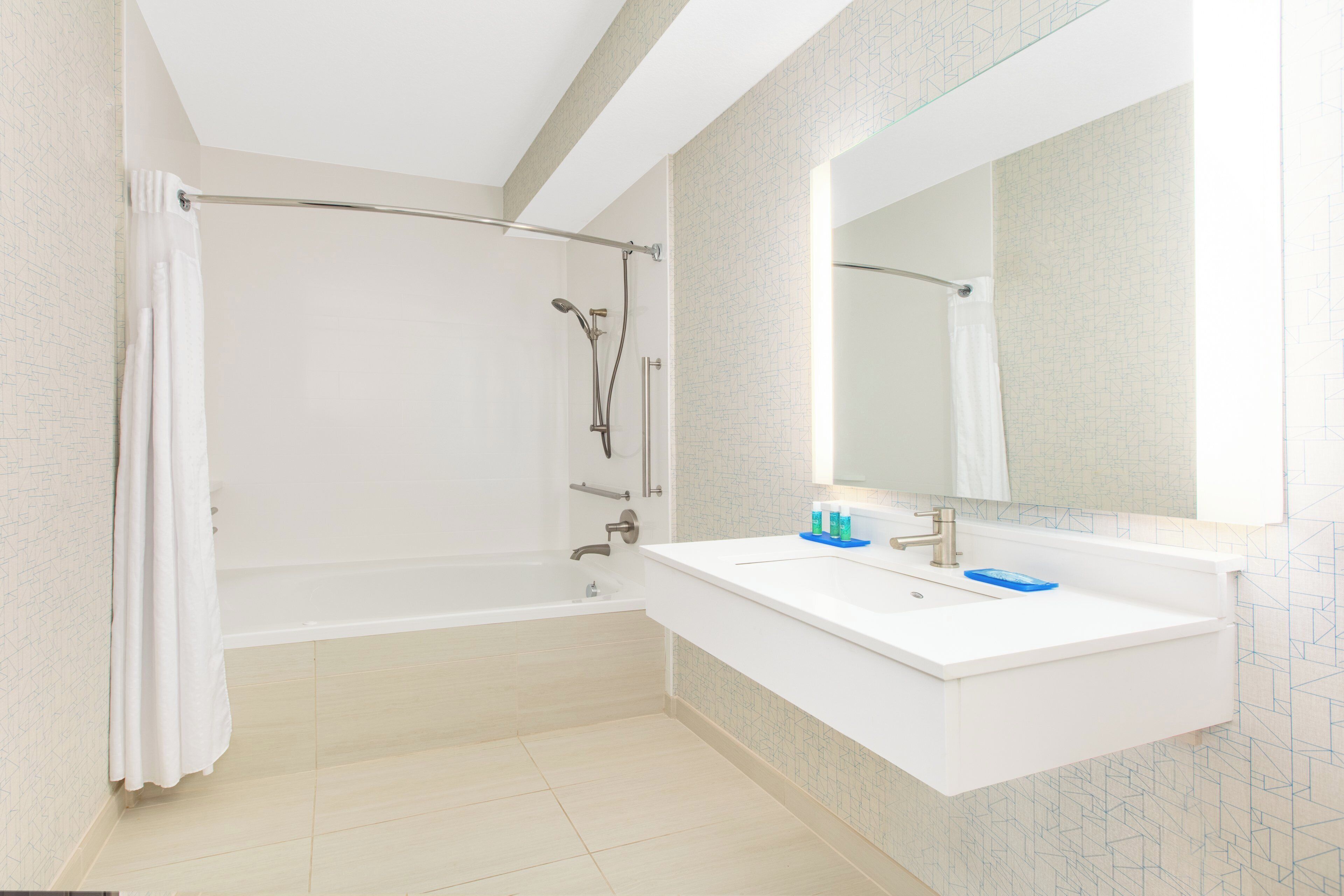 Un baño moderno con ducha a ras de suelo, un lavabo blanco y un espejo grande.