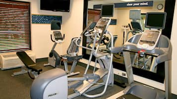 Une salle de sport équipée de divers appareils d’exercice, notamment des tapis de course, un vélo elliptique et un vélo d’appartement.