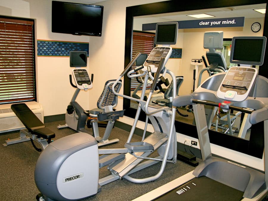 Une salle de sport équipée de divers appareils d’exercice, notamment des tapis de course, un vélo elliptique et un vélo d’appartement.
