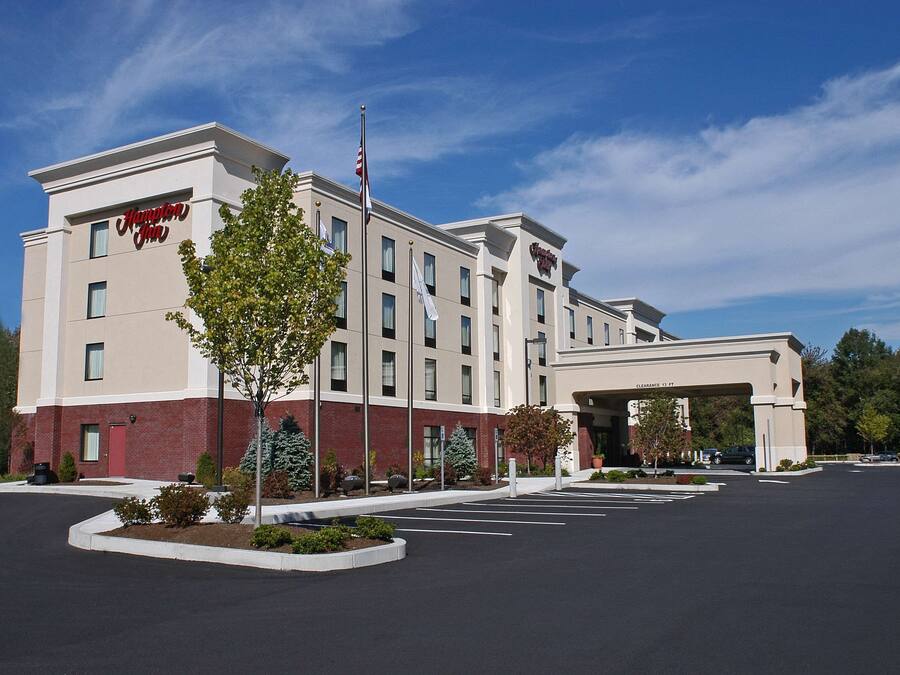 A Hampton Inn hotel with a parking lot and a clear sky.